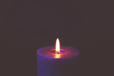 Une bougie allumée, seule, sur un fond sombre