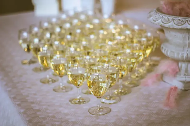 Des dizaines de coupes de champagne servies sur une nappe blanche, prêtes pour le toast
