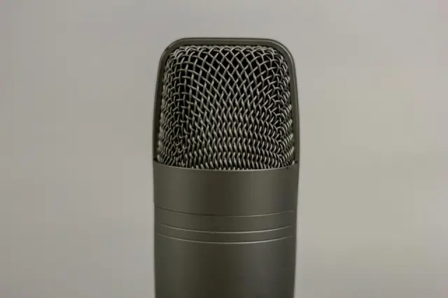 Un micro de studio gris vu de près, sur un fond gris clair